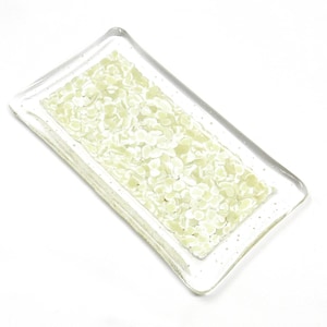 May include: A rectangular glass tray featuring a clear border and a central panel filled with small, pale green, rounded glass fragments. The surface has a smooth, glossy finish with a distinct layered texture created by the embedded pieces.