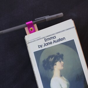 May include: A paperback copy of "Emma" by Jane Austen with a pink leather bookmark and a pen.