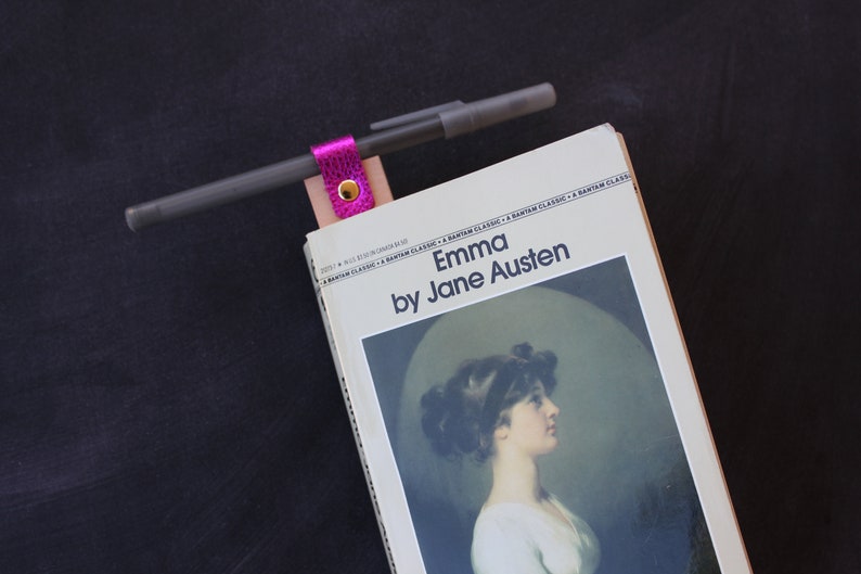 May include: A paperback copy of "Emma" by Jane Austen with a pink leather bookmark and a pen.