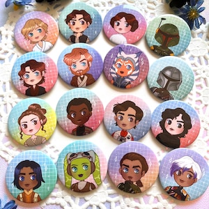 May include: A set of 15 round, colorful buttons featuring characters from the Star Wars franchise. The buttons are arranged in a circle on a white doily with a pink, blue, and purple background.