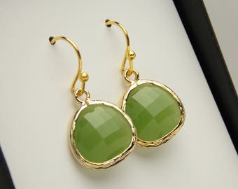 Puede incluir: Un par de pendientes de oro con gotas de piedras preciosas verdes. Los pendientes tienen un diseño delicado y texturizado.
