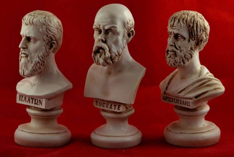 May include: Three white plaster busts of famous Greek philosophers: Plato, Socrates, and Aristotle. Each bust is on a white pedestal with the philosopher's name inscribed on the front.