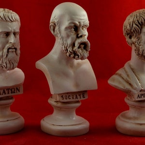 May include: Three white plaster busts of famous Greek philosophers on individual bases. The busts are of Plato, Socrates, and Aristophanes. Each bust has the philosopher's name inscribed on the base.