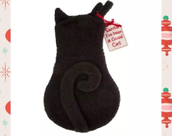 Peut inclure: Chaussette de Noël noire en forme de chat avec une queue enroulée et de petites oreilles. Une étiquette attachée avec un ruban rouge indique "Santa I've been a Good Cat". La chaussette est faite d'une matière douce et texturée.