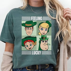 May include: Green t-shirt with a graphic featuring four cartoon characters in green hats, with the words "FEELING LUCKY" in a checkered pattern. The shirt is a solid green color.