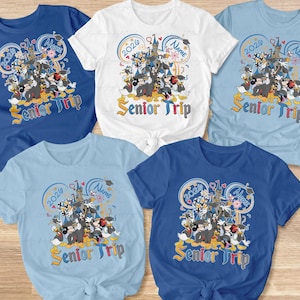 May include: Assorted-color t-shirts featuring a Disney-themed graphic with the text "Senior Trip" and "2026". The design includes cartoon characters and a castle. Available in blue, white, and light blue.