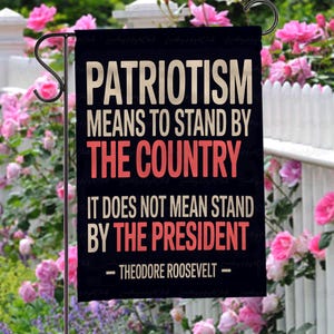 Puede incluir: Una bandera de jard&iacute;n negra con texto blanco y rojo que dice: "PATRIOTISMO SIGNIFICA APOYAR AL PA&Iacute;S, NO SIGNIFICA APOYAR AL PRESIDENTE - THEODORE ROOSEVELT -". La bandera est&aacute; colgada en un jard&iacute;n con flores rosas.