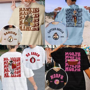 May include: Collection of t-shirts with various designs. One shirt is tan with "HAWKINS" and a cartoon figure. Another is light blue with "CAPTAIN AMELIA". A white shirt has "MR. ARROW". A black shirt has "MORPH". Each shirt has a matching circular design.