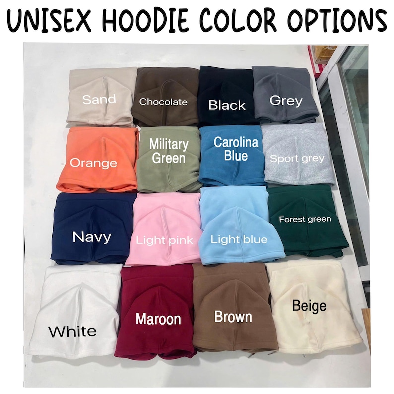 May include: A grid of folded unisex hoodies in various colours labelled with text including Sand, Chocolate, Black, Grey, Orange, Military Green, Carolina Blue, Sport grey, Navy, Light pink, Light blue, Forest green, White, Maroon, Brown, and Beige.