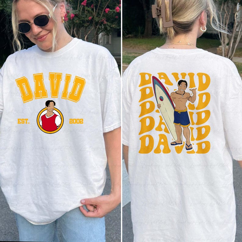 a woman wearing a t - shirt with a picture of a man holding a surf