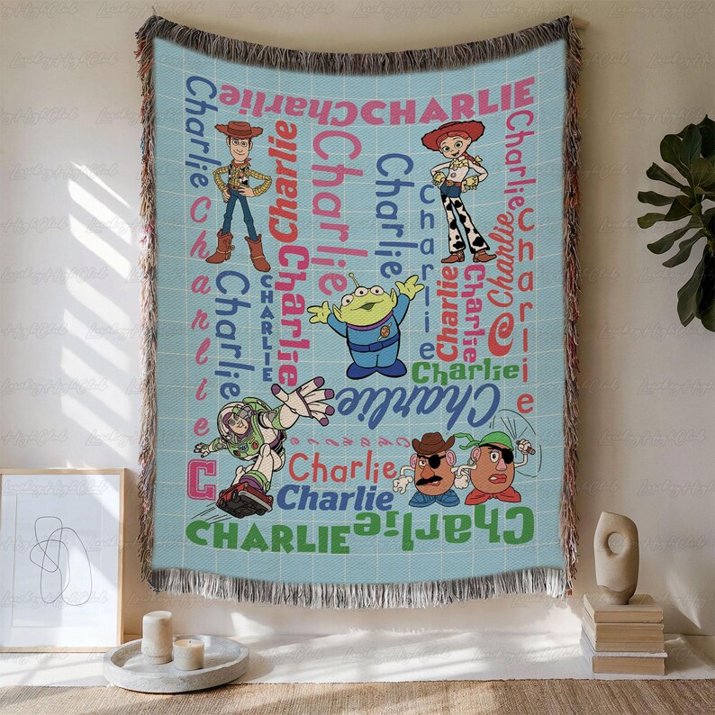 May include: A light blue woven throw blanket featuring a grid pattern and the name Charlie repeated in various colors and fonts. The blanket displays Toy Story characters including Woody, Jessie, Buzz Lightyear, and Mr. and Mrs. Potato Head.