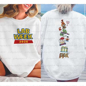 May include: White sweatshirt with the text "LAB WEEK 2026" in blue and yellow, with a red banner. The back of the sweatshirt features science-themed cartoon graphics, including a microscope and test tubes.