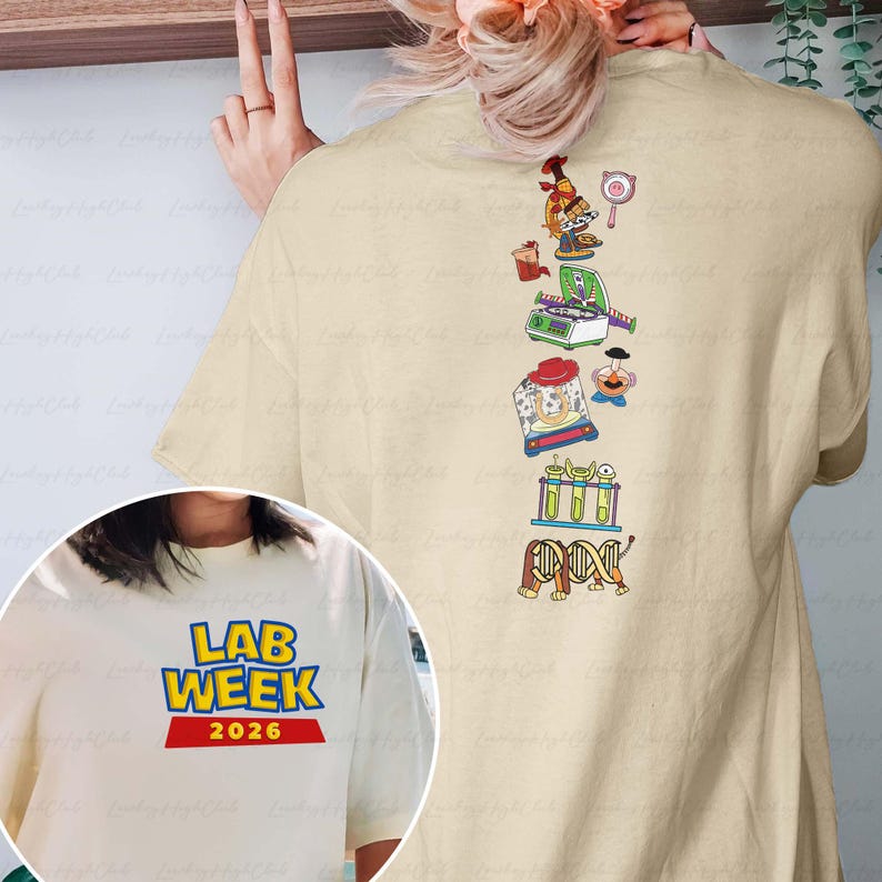 May include: Beige t-shirt with the text "LAB WEEK 2026" in blue and yellow. The back of the shirt features a vertical graphic of lab equipment and scientific illustrations in various colors, including a microscope and DNA strands.