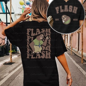 Puede incluir: Camiseta negra con un gr&aacute;fico de perezoso marr&oacute;n y el texto "FLASH" en una fuente retro. El perezoso lleva una camisa verde y una corbata y sostiene un cartel que dice "FLASH". El texto "EST. 2016" tambi&eacute;n est&aacute; en la camiseta.