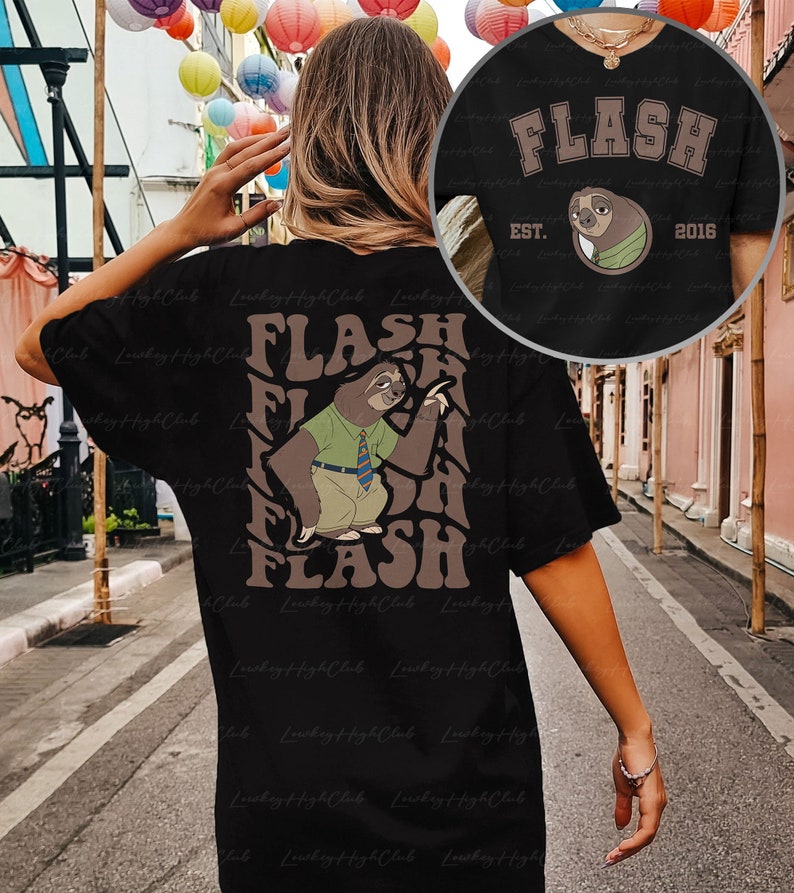 Puede incluir: Camiseta negra con un gr&aacute;fico de perezoso marr&oacute;n y el texto "FLASH" en una fuente retro. El perezoso lleva una camisa verde y una corbata y sostiene un cartel que dice "FLASH". El texto "EST. 2016" tambi&eacute;n est&aacute; en la camiseta.