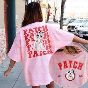 May include: Pink oversized t-shirt with a red graphic of a Dalmatian dog and the word "PATCH" repeated in a retro font. The back of the shirt features a smaller graphic of a Dalmatian dog with the text "PATCH EST. 1961".