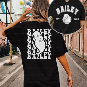 May include: Black t-shirt with a white graphic of the word "BAILEY" repeated in a circular pattern. The graphic also includes a white cartoon image of a whale. The text "EST. 2016" is also included in the graphic.