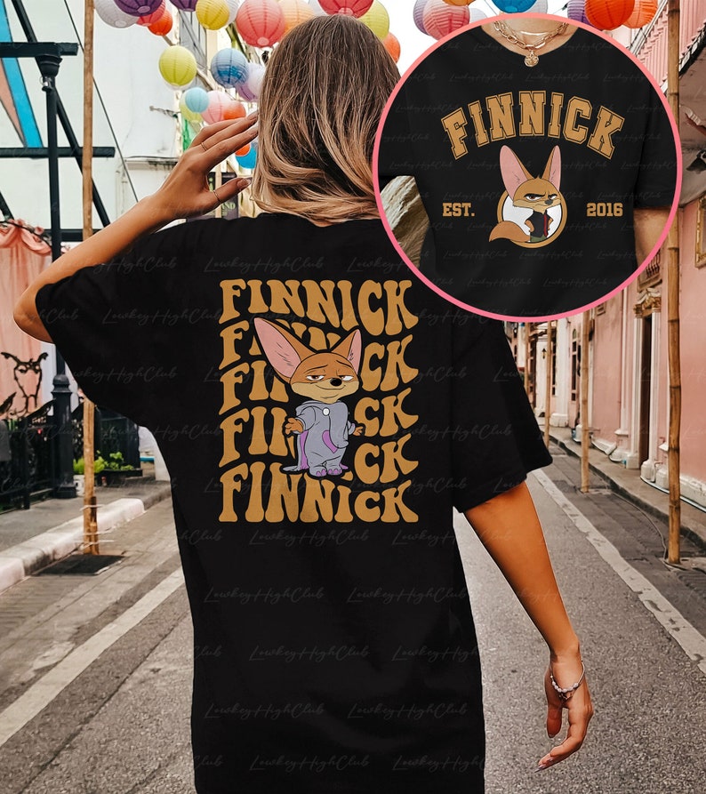 May include: Black t-shirt with a graphic print of a cartoon fox wearing a purple jacket and the text "FINNICK" in a retro font. The text "EST. 2016" is also printed on the shirt.
