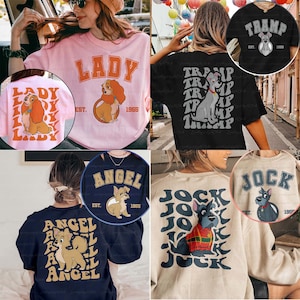 May include: A collection of t-shirts and sweatshirts featuring cartoon dog characters. Designs include "Lady", "Tramp", "Angel", and "Jock", with the year "1955" or "1966" and the character's name in bold lettering. The shirts are in various colors.