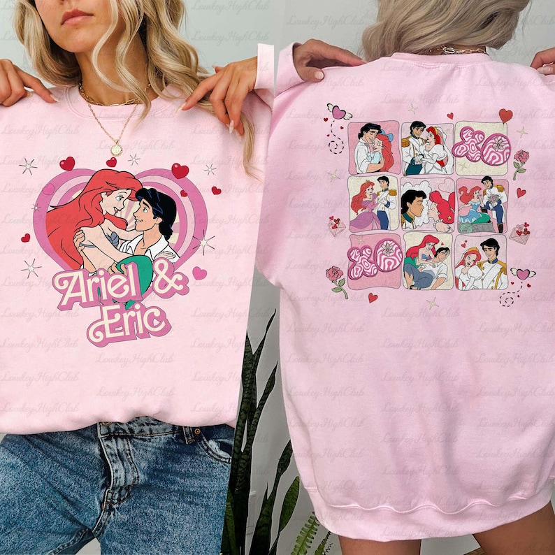 May include: Pink sweatshirt featuring a graphic of Ariel and Eric embracing within a heart, with the text "Ariel & Eric." The back of the sweatshirt displays a grid of Ariel and Eric illustrations. Hearts and floral accents complete the design.