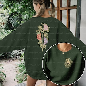 May include: Two green sweatshirts with different designs. One sweatshirt has a gold outline of a dagger with flowers and the text "Where is my mind?" The other sweatshirt has a gold outline of a ram's head with flowers.