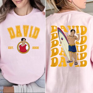a woman wearing a pink shirt with a picture of a man holding a surfboard