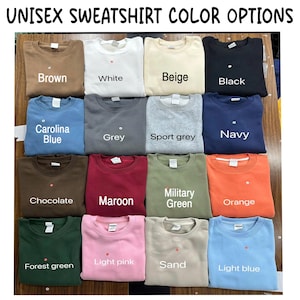 May include: A collection of sixteen crewneck sweatshirts in various colours including brown, white, beige, black, Carolina blue, grey, sport grey, navy, chocolate, maroon, military green, orange, forest green, light pink, sand, and light blue.