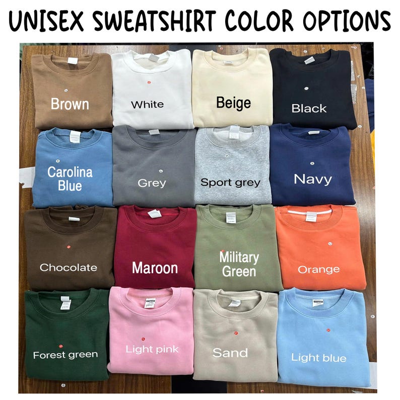 May include: A collection of sixteen crewneck sweatshirts in various colours including brown, white, beige, black, Carolina blue, grey, sport grey, navy, chocolate, maroon, military green, orange, forest green, light pink, sand, and light blue.