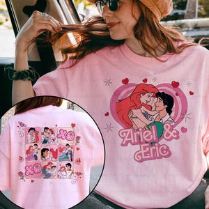 May include: Pink t-shirt featuring a graphic of Ariel and Eric embracing within a heart-shaped frame, with the text "Ariel & Eric". The back of the shirt displays a collage of Ariel and Eric images.