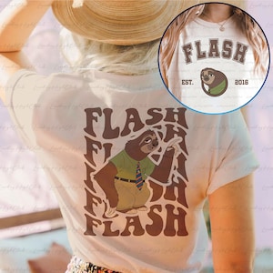Puede incluir: Camiseta blanca con un gr&aacute;fico de perezoso marr&oacute;n y el texto "FLASH" en una fuente retro. El perezoso lleva una camisa verde y una corbata azul. El texto "EST. 2016" tambi&eacute;n est&aacute; en la camiseta.