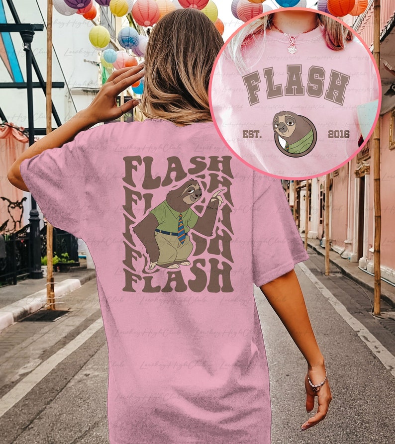 Puede incluir: Camiseta rosa con un gr&aacute;fico de perezoso marr&oacute;n y el texto "FLASH" repetido en un patr&oacute;n ondulado. El perezoso lleva una camisa verde y una corbata. El texto "EST. 2016" tambi&eacute;n est&aacute; en la camiseta.