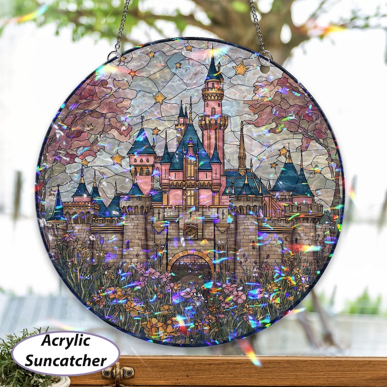 May include: Round acrylic suncatcher featuring a colorful stained-glass design of a fairytale castle with pink, blue, and gray tones. The castle is surrounded by flowers and stars, with the text "Acrylic Suncatcher".