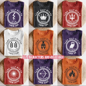 May include: Nine t-shirts in various colors, each featuring a circular design with the words "CAMP HALF-BLOOD" and a Greek god symbol. The text "ALL CHARACTERS ARE AVAILABLE" is also present.