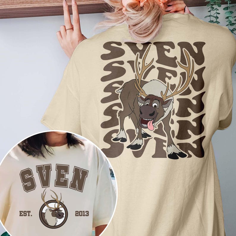Pode incluir: Camiseta bege com um desenho de rena de desenho animado e o nome "SVEN" repetido. A frente da camiseta mostra "SVEN", um gr&aacute;fico de rena e o texto "EST. 2013".