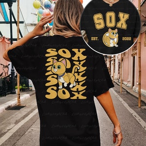 May include: Black t-shirt with a yellow graphic of a cat and the word "SOX" repeated vertically. The cat is wearing a collar with a tag. The text "EST. 2022" is below the graphic.