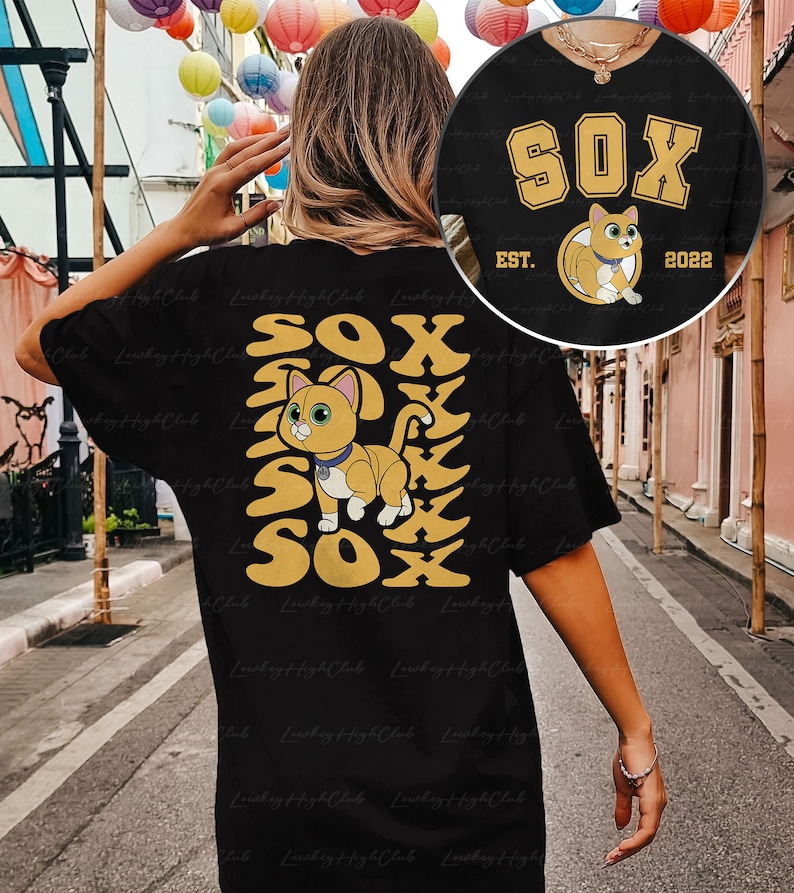May include: Black t-shirt with a yellow graphic of a cat and the word "SOX" repeated vertically. The cat is wearing a collar with a tag. The text "EST. 2022" is below the graphic.