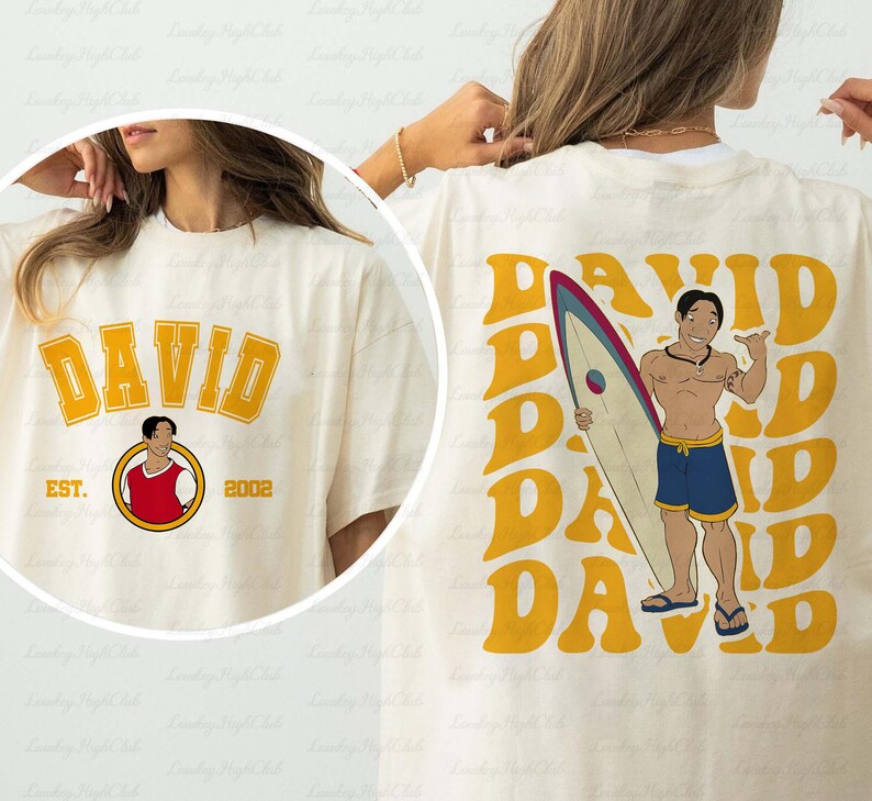 a woman wearing a t - shirt with a picture of a man holding a surf