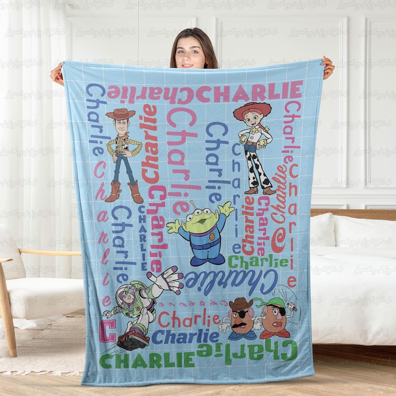 May include: A light blue fleece blanket featuring a grid pattern and the name Charlie repeated in various colors and fonts. The blanket displays cartoon characters including Woody, Jessie, an alien, Buzz Lightyear, and Mr. Potato Head.