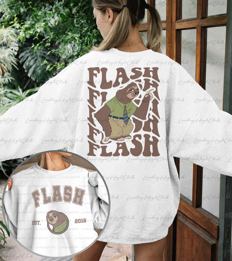 Puede incluir: Sudadera blanca con un gr&aacute;fico de perezoso marr&oacute;n y el texto "FLASH" en una fuente retro. El perezoso lleva una camisa verde y una corbata. La sudadera tambi&eacute;n tiene un gr&aacute;fico m&aacute;s peque&ntilde;o en la parte delantera con el texto "FLASH" y el a&ntilde;o "2016".