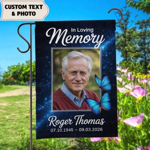Può includere: Una bandiera da giardino personalizzata con foto e testo. Presenta un ritratto di un uomo, farfalle blu e le parole "In Loving Memory" e "Roger Thomas" con date. Lo sfondo è blu scuro con un motivo a stelle.