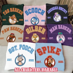 May include: Collection of colorful throw pillows featuring cartoon dog characters with names like "Tag Barker" and "Scooch." Each pillow has a character image, the name in arched text, and the text "EST. 2021." The bottom text reads "ALL CHARACTERS AVAILABLE."