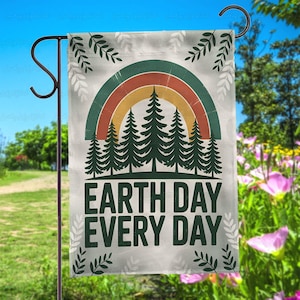 May include: A rectangular garden flag with a rainbow, evergreen trees, and the text "EARTH DAY EVERY DAY" in green and white. The flag is hanging on a black metal stand, with a blue sky and green foliage in the background.