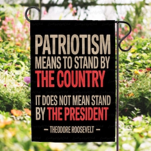 Puede incluir: Bandera de jard&iacute;n negra con la cita "PATRIOTISMO SIGNIFICA APOYAR AL PA&Iacute;S, NO SIGNIFICA APOYAR AL PRESIDENTE - THEODORE ROOSEVELT -" en texto blanco y rojo. La bandera est&aacute; colgada de un soporte de metal negro.