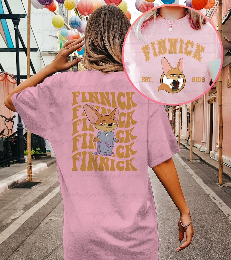 May include: Pink t-shirt with a cartoon fox wearing a purple jacket and the text "Finnick" repeated in a retro font. The text "Est. 2016" is also on the shirt.