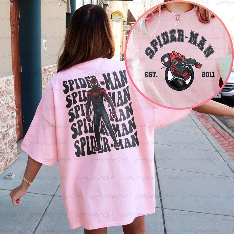 May include: Pink oversized t-shirt with a black and red Spider-Man graphic on the back. The front of the shirt has the text "SPIDER-MAN EST. 2011" in black.