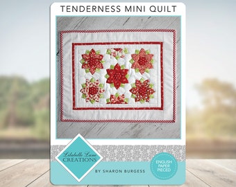May include: A red, green, and white mini quilt with a floral design. The quilt is titled "Tenderness Mini Quilt" and is by "Lilabelle Lane Creations" by Sharon Burgess. The quilt is English paper pieced.