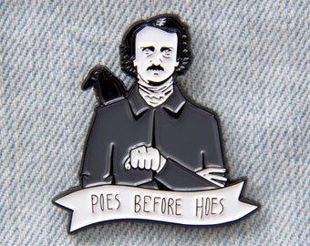 May include: Black and white enamel pin featuring a cartoon illustration of Edgar Allan Poe with a raven on his shoulder. The pin has a white banner with the text "POES BEFORE HOES".