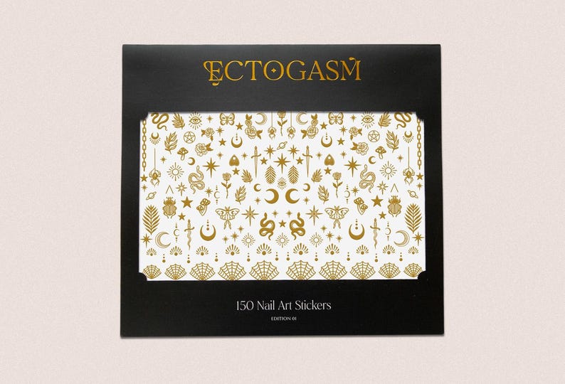 K&ouml;nnte beinhalten: Schwarze Schachtel mit goldenem Text &bdquo;ECTOGASM&ldquo; und einem wei&szlig;en Hintergrund mit goldenen Nagelkunst-Aufklebern mit himmlischem und mystischem Thema. Auf der Schachtel steht &bdquo;150 Nail Art Stickers&ldquo; und &bdquo;Edition III&ldquo;.