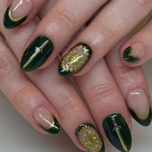 May include: Dark green nail art with gold accents. Some nails feature a gold sword design, while others showcase a gold four-leaf clover. The nails have a glossy finish, with a French tip design in gold.