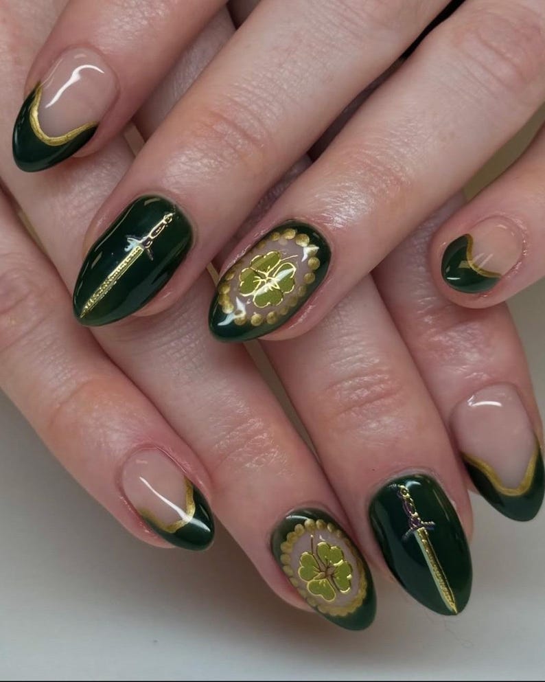 May include: Dark green nail art with gold accents. Some nails feature a gold sword design, while others showcase a gold four-leaf clover. The nails have a glossy finish, with a French tip design in gold.